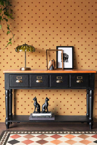 The Sacred Hearts Wallpaper in Golden Hour shown in a hallway with a black console table. 