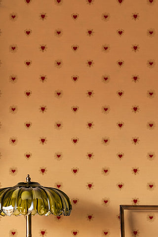 The Sacred Hearts Wallpaper in Golden Hour shown with a green glass table lamp. 