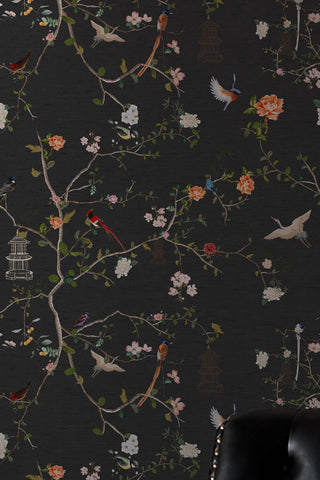 Close up of The Secret Garden Chinoiserie Wallpaper in Black Ink with an armchair in the corner. 