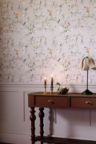The Secret Garden Chinoiserie Wallpaper in Dusty Lilac shown in a hallway with red console table and table lamp.