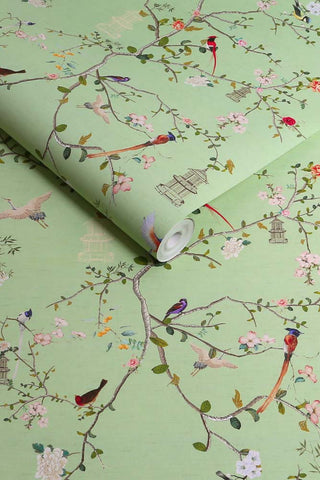 The roll of The Secret Garden Chinoiserie Wallpaper in Green Tea. 