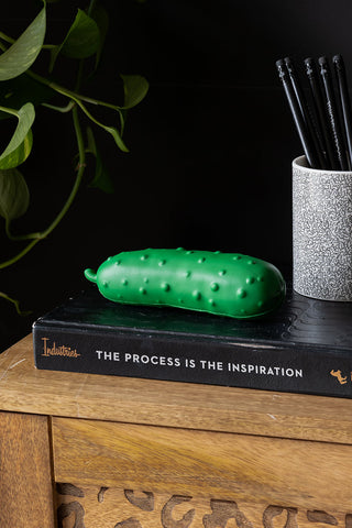 The Stress Pickle displayed on a book with some pencils.