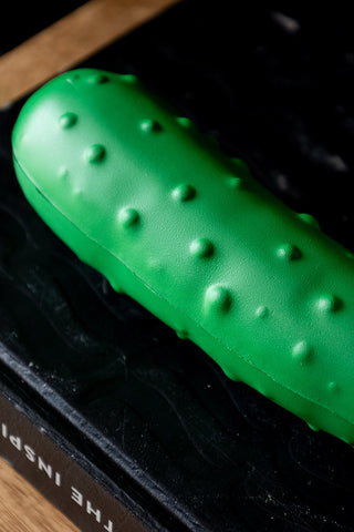 Close-up of the The Stress Pickle on a wooden sideboard.