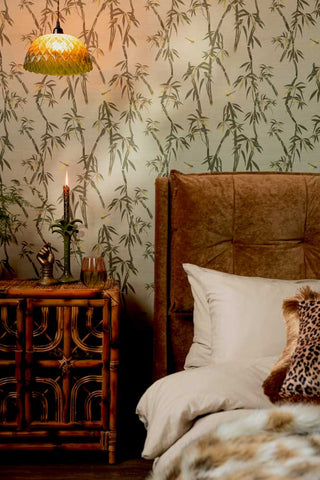 The Wham Bamboo Wallpaper in Sage Green shown in a bedroom with a gold velvet bed and a bamboo cabinet. 