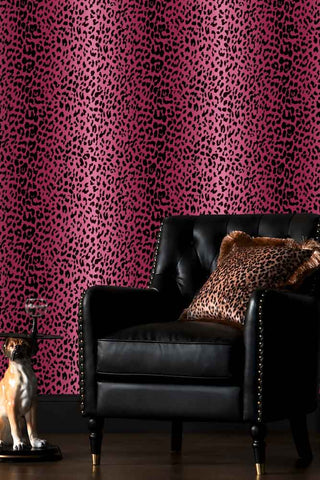 The Wild At Heart Wallpaper in Pink in a living room with a black faux leather armchair.
