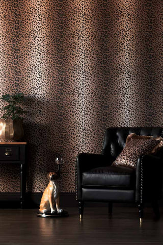 The Wild At Heart Wallpaper in Tan shown in a living room with a black faux leather armchair and a dog side table. 