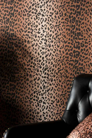 A close up of The Wild At Heart Wallpaper in Tan with an armchair in the corner. 