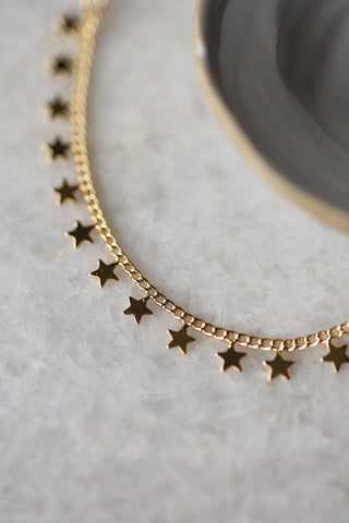 Detail image of the You're A Star Charm Gold Bracelet displayed on a marble table. 