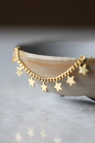 Lifestyle image of the You're A Star Charm Gold Bracelet displayed hanging from a bowl. 
