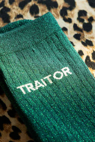 Detail of the Traitor Green Glitter Socks shown against a leopard print background. 