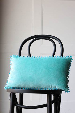 Lifestyle image of the Velvet Pom Pom Cushion In Aqua