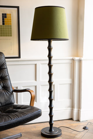 The Vintage-Inspired Floor Lamp With Green Lampshade displayed next to a swivel chair and art print.