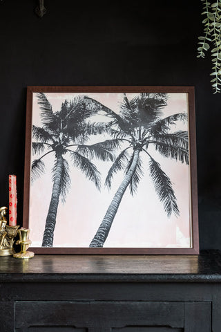 Lifestyle image of Vintage Pink Palms 50cm x 50cm Art Print in a walnut frame on a dark background.