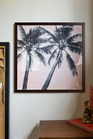 Lifestyle image of Vintage Pink Palms 50cm x 50cm Art Print in a walnut frame on a light background.