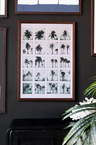 Framed artwork of palm trees on a dark wall with decorative elements.