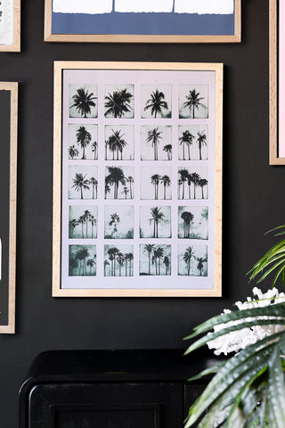 Framed artwork of palm trees on a dark wall with decorative elements.