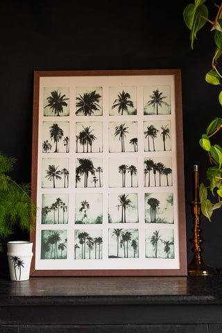 Lifestyle image of the Vintage-Style Polaroid Palms A2 Art Print in a walnut frame on a dark background.