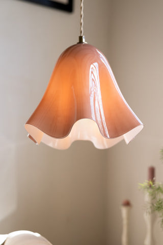 The Blush Wavy Glass Pendant Light shown with the light on, against white walls. 