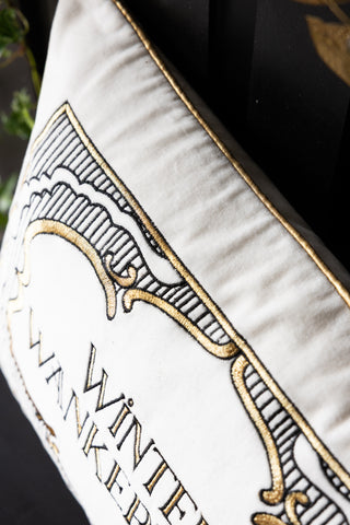 Decorative pillow with gold embroidery and text on a white background