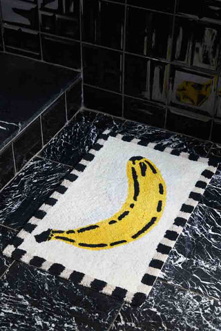 Lifestyle image of the Yellow Banana Bath Mat on a black floor