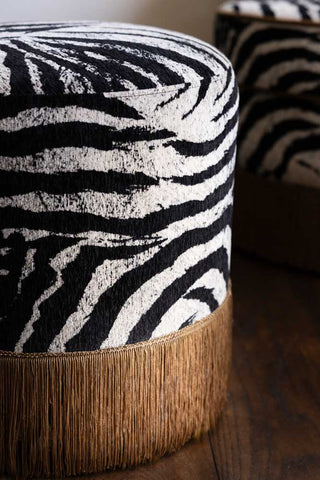 A detail image of the Zebra Print Tassel Footstool, shown from the side with focus on the zebra pattern and gold fringing.