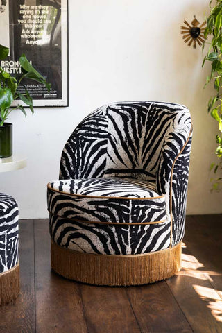 Image of Zebra Print Tassel Swivel Chair shown in a neutral room surrounded by plants.