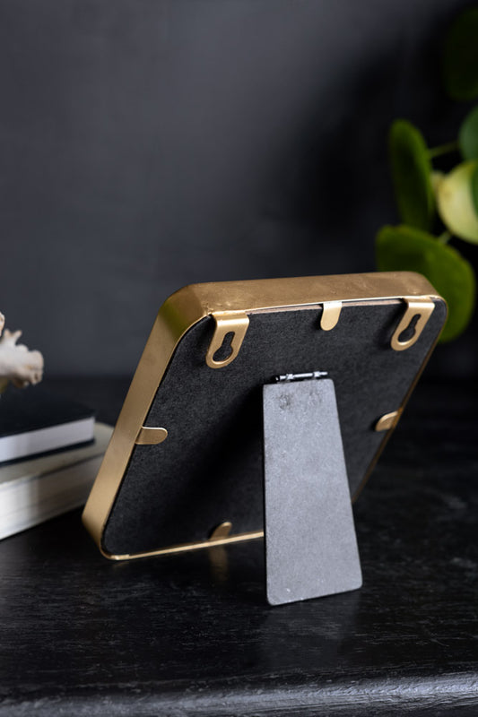 The Zero Fucks Gold Ornament seen from the back, displayed on a dark surface with some greenery and other accessories.