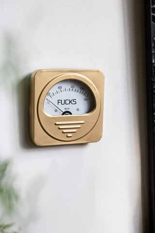 The Zero Fucks Gold Ornament displayed on a white wall.