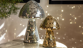 The Small & Large Disco Mushroom Ornaments displayed together on a table, reflecting light onto the wall behind.