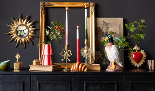 A black sideboard styled with various ornaments, candles and greenery.