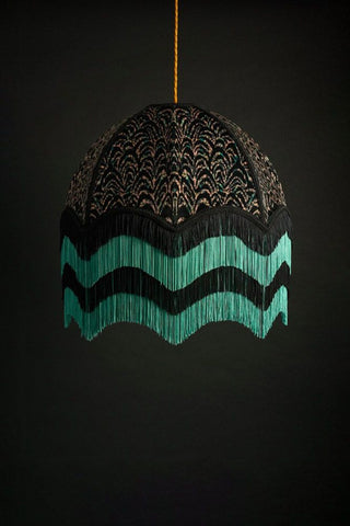A Anna Hayman lampshade in a simple black pattern with a teal and black fringing on the bottom. 