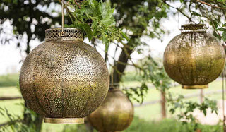 Image of three Antique Brass Moroccan Solar Lanterns handing in a tree. 