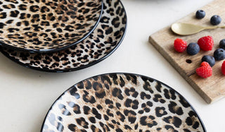 The Set of 4 Natural Leopard Love Side Plates displayed on a white surface with a wooden serving board, spoon and some berries.