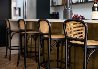 Lifestyle image of four Chez Pitou Black Wood & Woven Cane Bar Stools in a kitchen setting.  