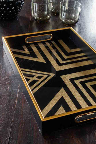 Close up image of a black and gold rectangle tray in a geometric pattern. 