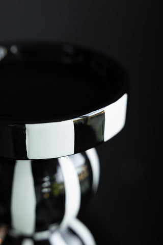 Close-up of a black and white candle holder on a dark background.