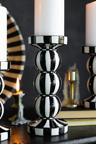 Close-up of a black and white striped candle holder, styled with others in the background as well as some other home accessories.