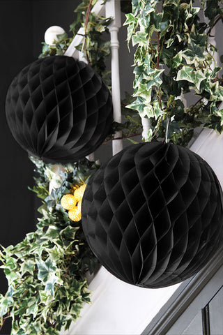 Set of two honeycomb black paper balls hanging from bannisters styled with ivy.