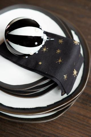 White and black dinner and side plates stacked with a black and white bauble and gold napkin