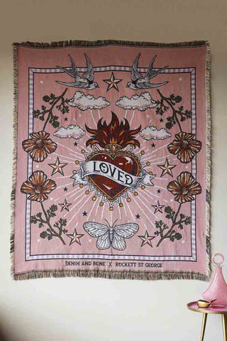 A pretty pink throw that's been put on the wall. The throw features a a large heart, flowers, butterflies and stars. 