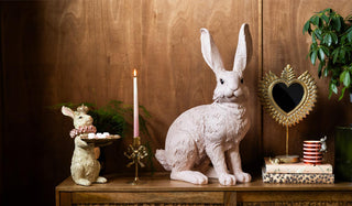 Decorative rabbit figures on a wooden surface with candles and small objects.