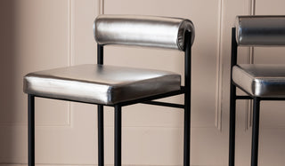 Two silver bar stools styled in front of a neutral panelled wall.