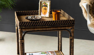 The Dark Brown Rattan Side Table styled with magazines and various decorative accessories.