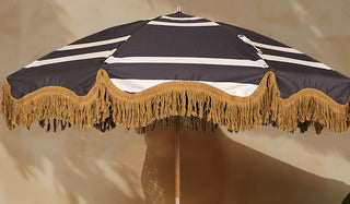 The HKliving Stripe Parasol displayed in front of a neutral wall in the sunshine.