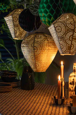 Lifestyle image of the Gold Bell Solar Garden Lantern styled on a garden table with candlesticks.