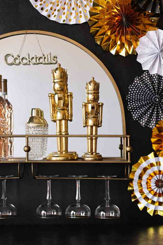 Two gold nutcrackers (large and small) on a gold bar shelf with mirror