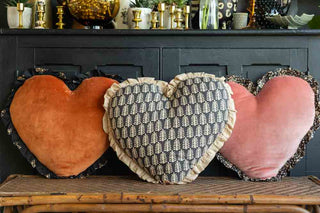 Three heart cushions on a woven cane bench.