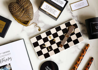 A flat lay image taken from above, showing an array of gifts. A checkerboard dish, leopard print candles and an angel wing dish. 