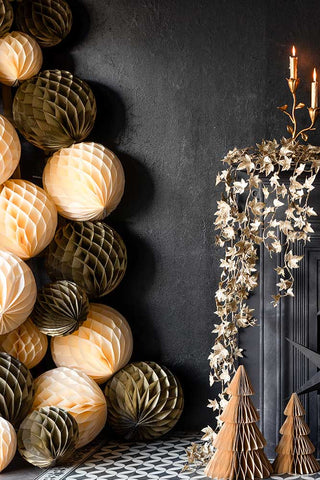 Ivory and gold honeycomb balls stacked on top of one another to make a christmas tree.