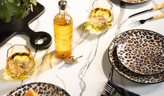A tablescape styled with leopard print plates and varius other acessories.